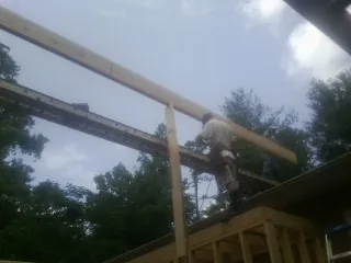 Carpenter setting a ridge beam over a new addition frame — Ice Dam Removal by Roofing Brothers in Abie
