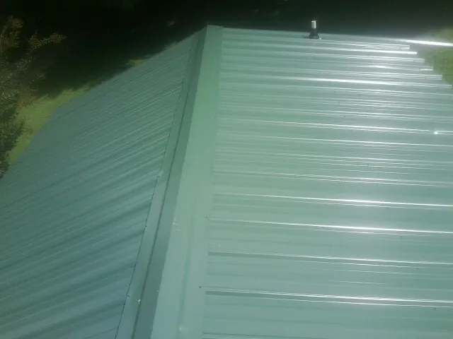 New green metal panels meeting at the ridge of a roof — Flat Roof Repair work by our crew in Abie