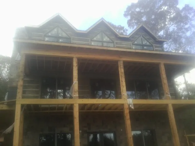 Dormers and porch framing on a large log home under construction — Roof Coating work by our crew in Abie
