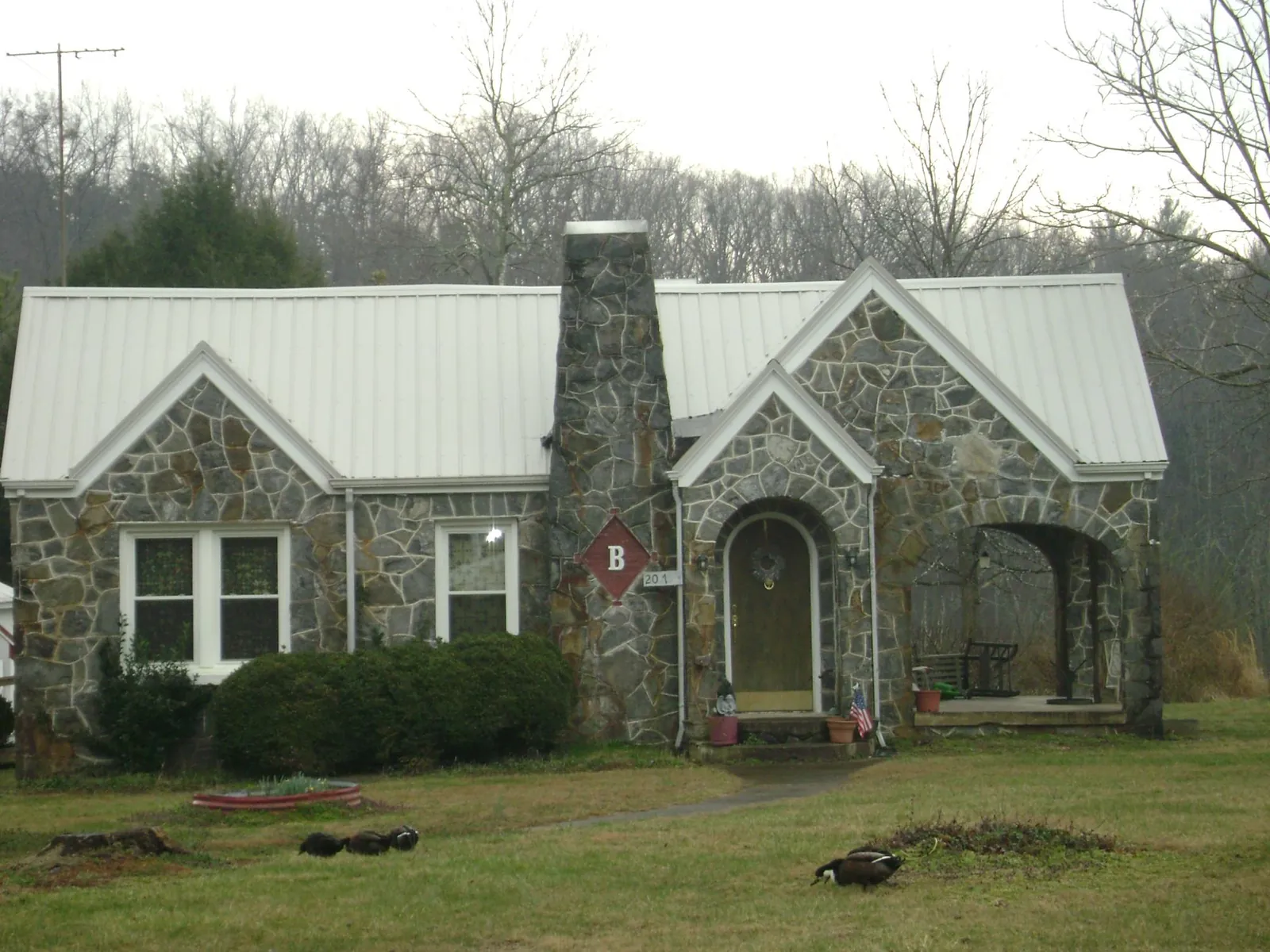 White metal roof on a stone cottage with steep gables in Abie