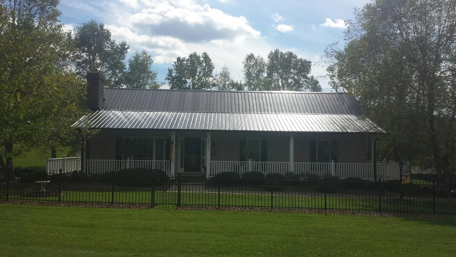 Gray metal roof on a brick ranch with a full width front porch — Gutter Guard Installation work by our crew in Abie
