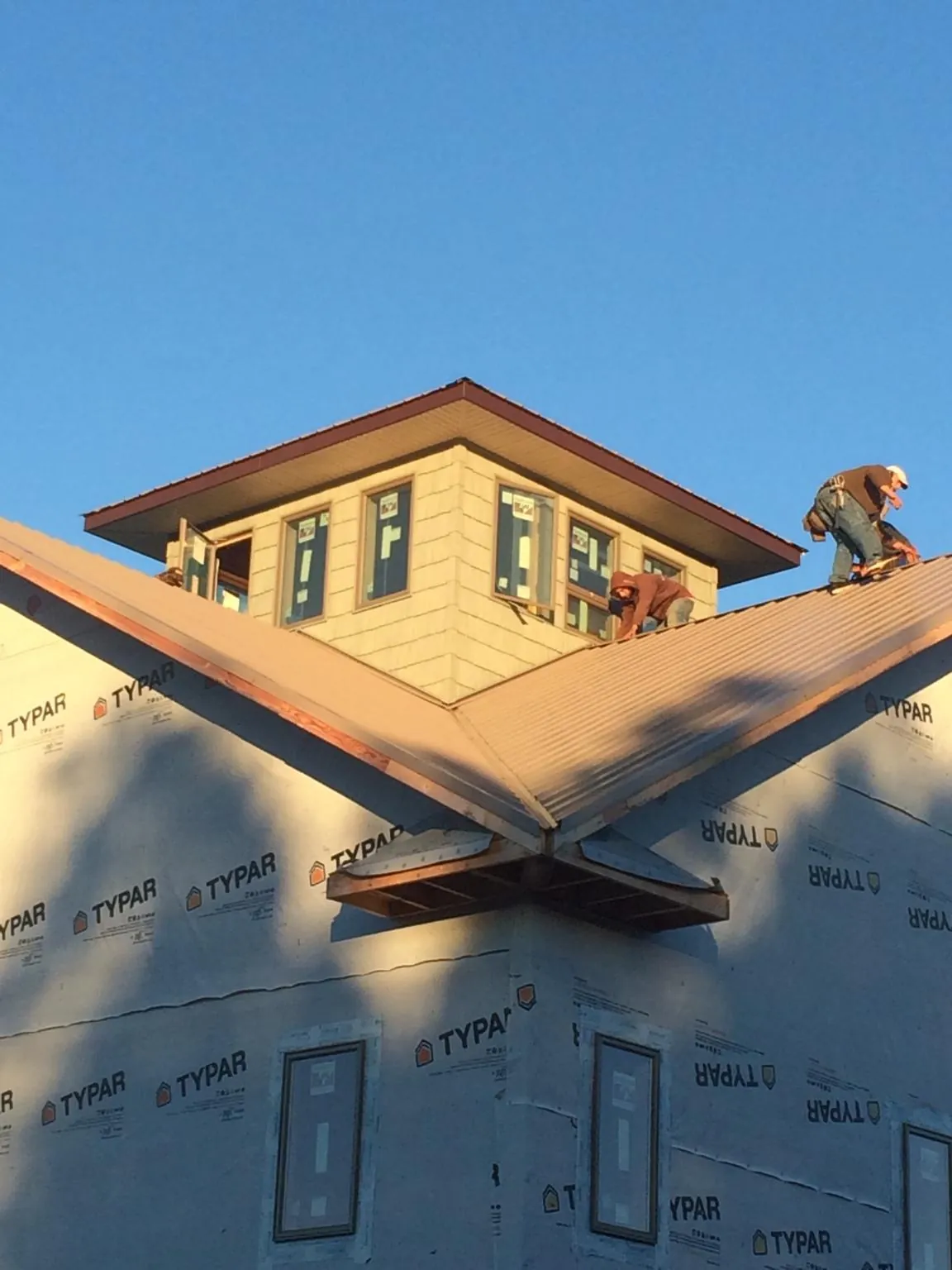Roofers working around a rooftop cupola on a new metal roof at sunset — Roof Waterproofing in Abie by Roofing Brothers